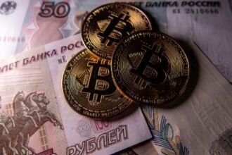 Novelty Bitcoin tokens are photographed besides Russian rouble bank notes.