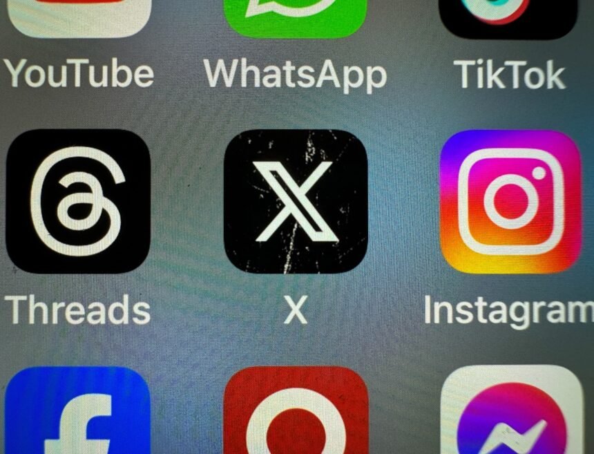 In this photo illustration the logo of US online social media and social networking site 'X' (formerly known as Twitter) is displayed centrally on a smartphone screen alongside that of Threads and Instagram