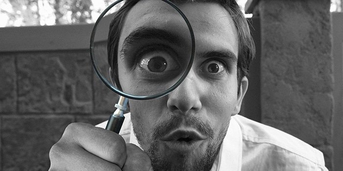 Una persona con una lupa observando algo detalladamente.