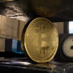 Bitcoin coin pinned beneath a heavy press beside a pressure gauge in a central bank setting, symbolizing Bitcoin’s recovery running into a Fed ceiling without cheaper money